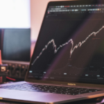 laptop with stock chart open and books in background