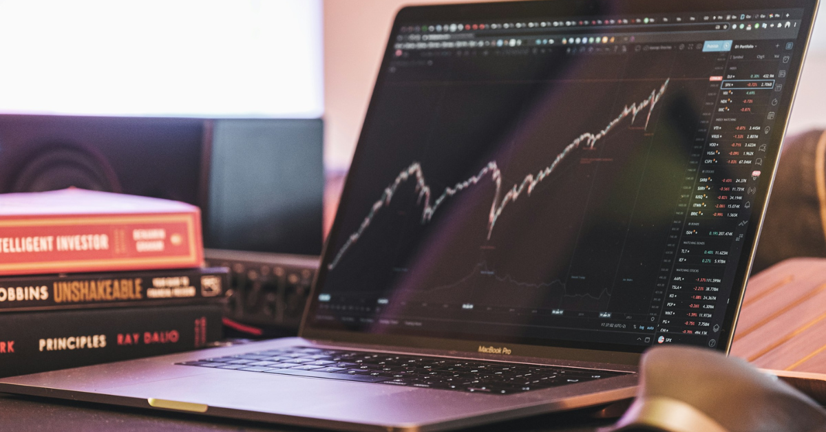 laptop with stock chart open and books in background